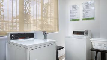 A laundry area with two washing machines, a dryer, and a notice board.
