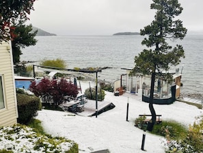 Ein Küstenanwesen mit einer Terrasse, Sitzmöglichkeiten im Freien und Blick auf das Meer.