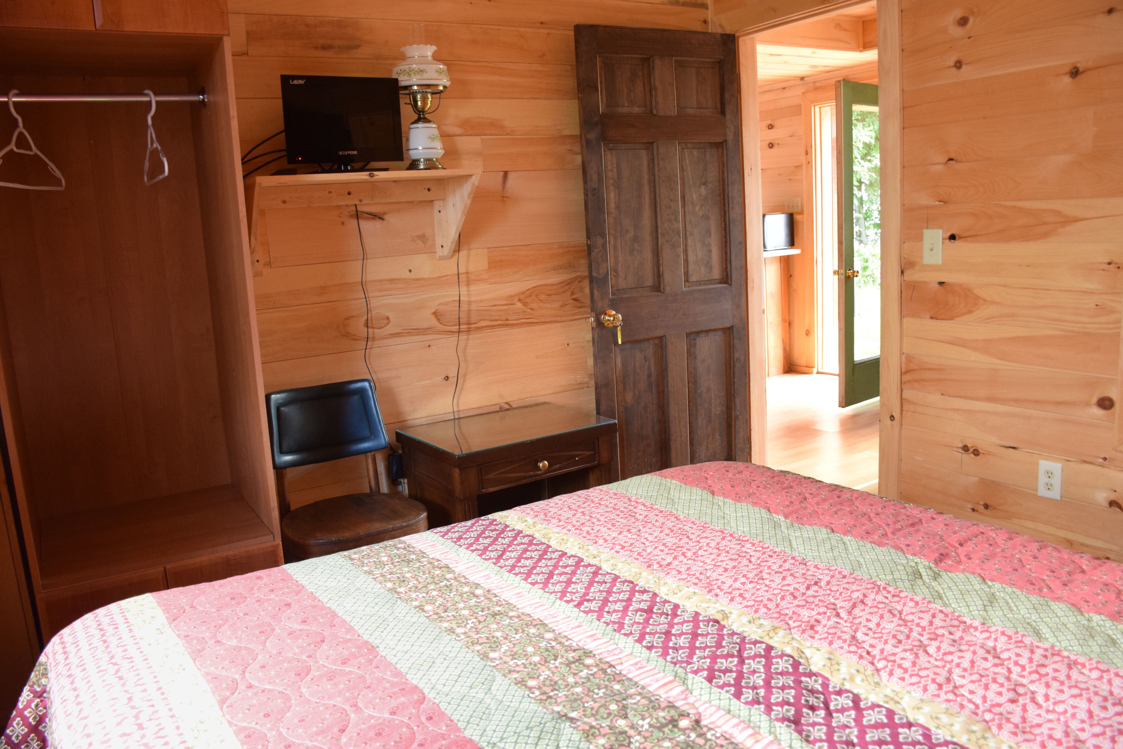 A wooden room with a bed, a desk, and a wardrobe.