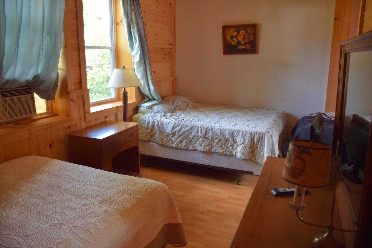 A cozy room with a bed, a desk, a lamp, and a painting on the wall.
