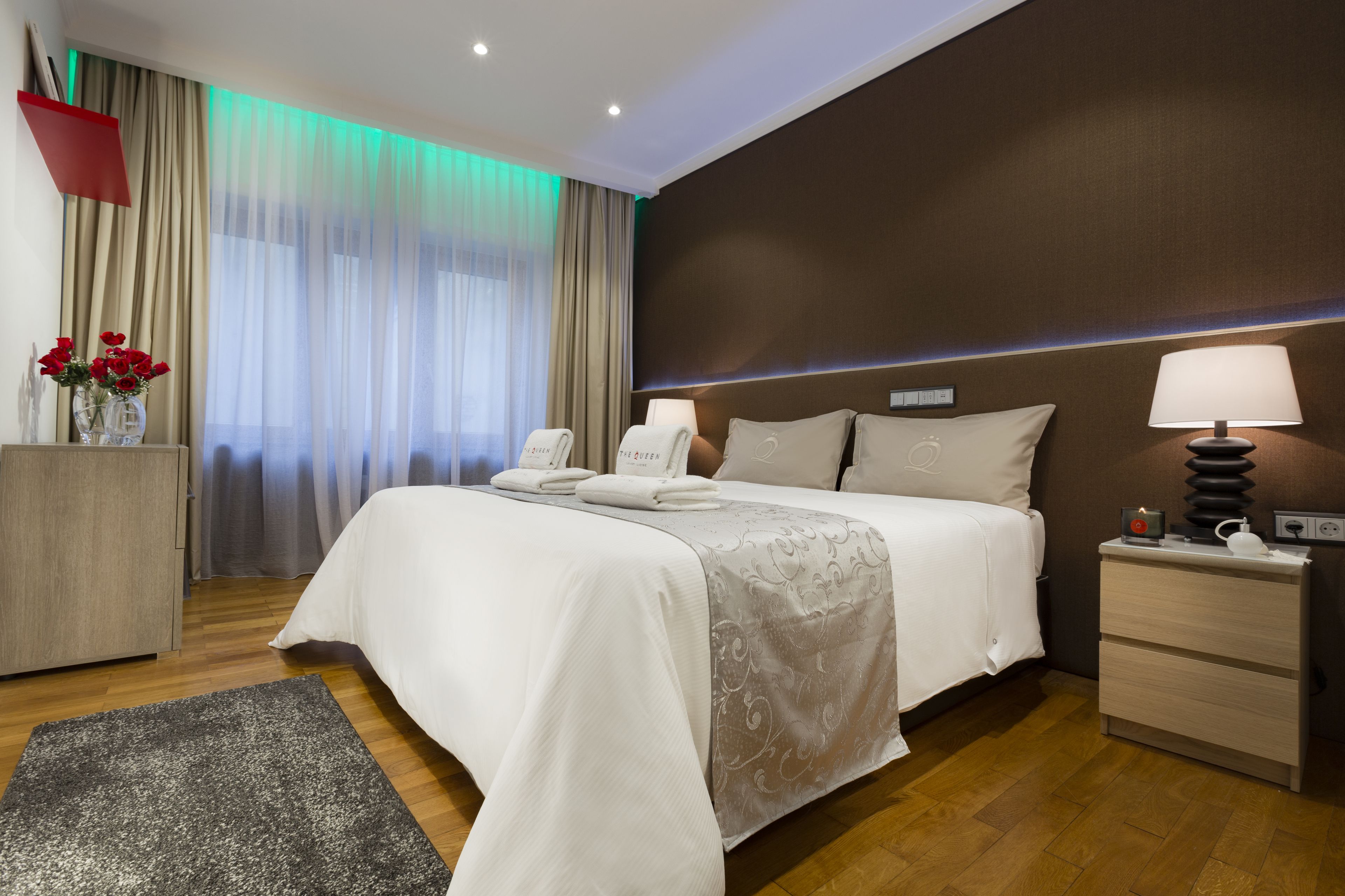 A hotel room with a bed, bedside tables, a nightstand, a desk, and a chair.