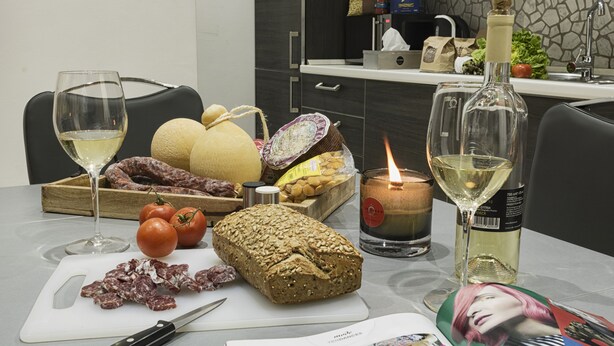 A table with food items, a bottle of wine, and a candle. - The Queen Luxury Apartments - Villa Liberty (Luxembourg City)