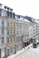 Vista de calle con edificios históricos, un autobús y peatones.