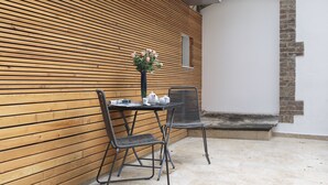 An outdoor seating area with a wooden wall, a table with chairs, and a vase of flowers. - The Queen Luxury Apartments - Villa Liberty (Luxembourg City)