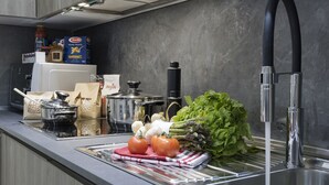 A modern kitchen with a stainless steel sink, a variety of fresh vegetables, and kitchen appliances. - The Queen Luxury Apartments - Villa Liberty (Luxembourg City)