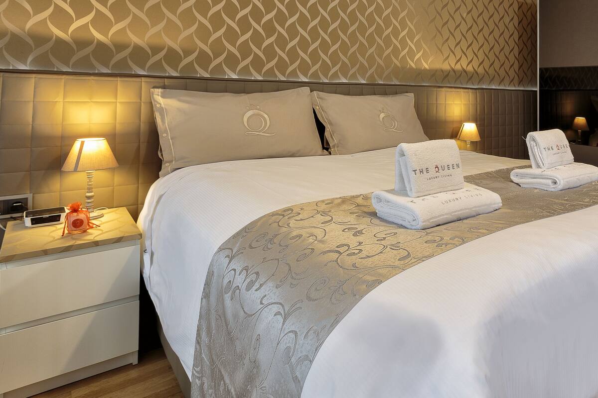 Habitación de hotel con una cama grande, dos lámparas de noche, una mesita y un espejo.