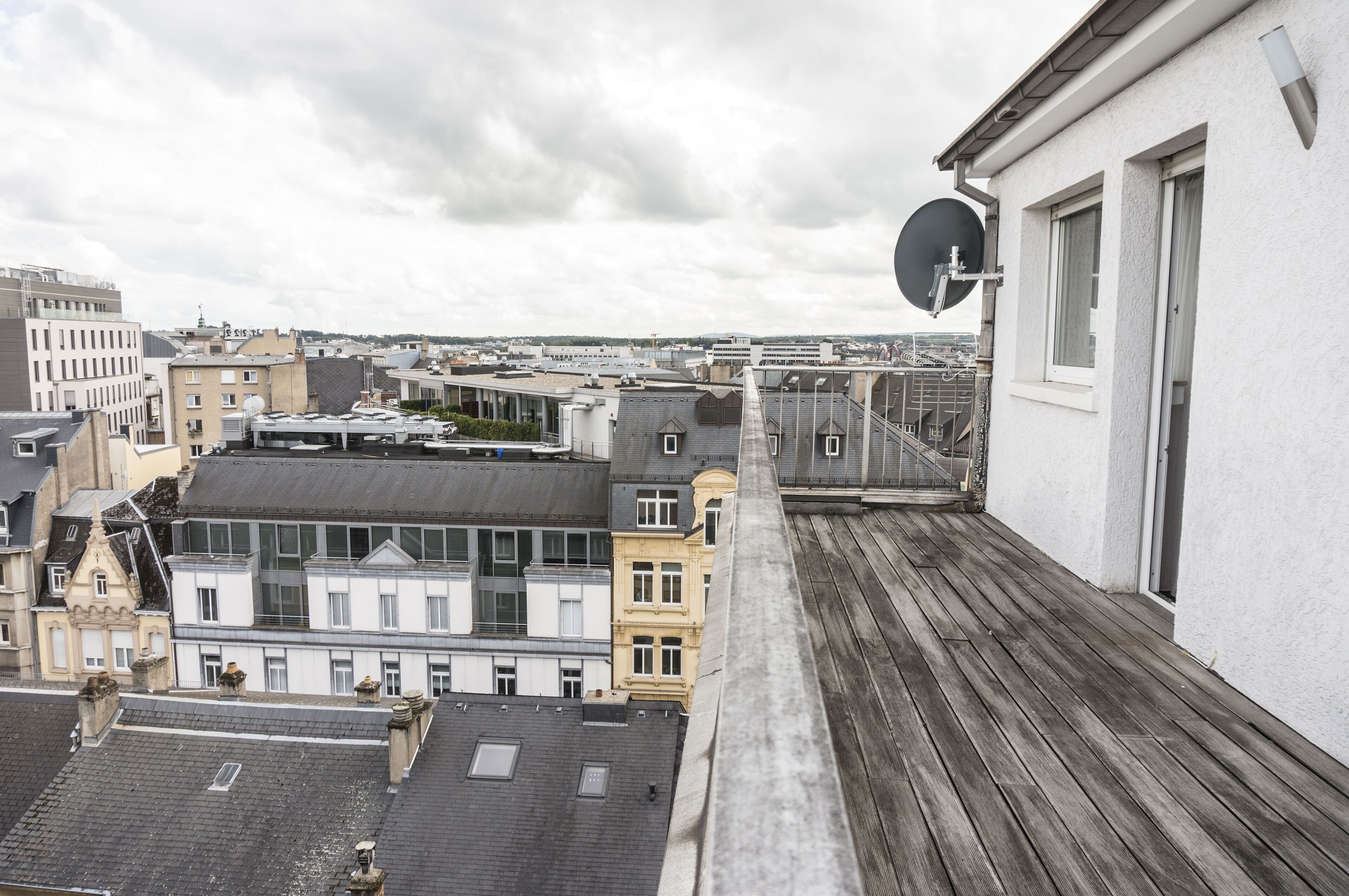 A rooftop terrace with a view of surrounding buildings and a satellite dish.