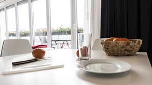 A dining table with a white plate, a knife, a bowl of fruit, and a woven basket. - The Queen Luxury Apartments - Villa Fiorita (Luxembourg City)