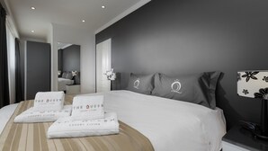 A modern hotel room with a large bed, a bedside table, a lamp, and a mirror. - The Queen Luxury Apartments - Villa Fiorita (Luxembourg City)