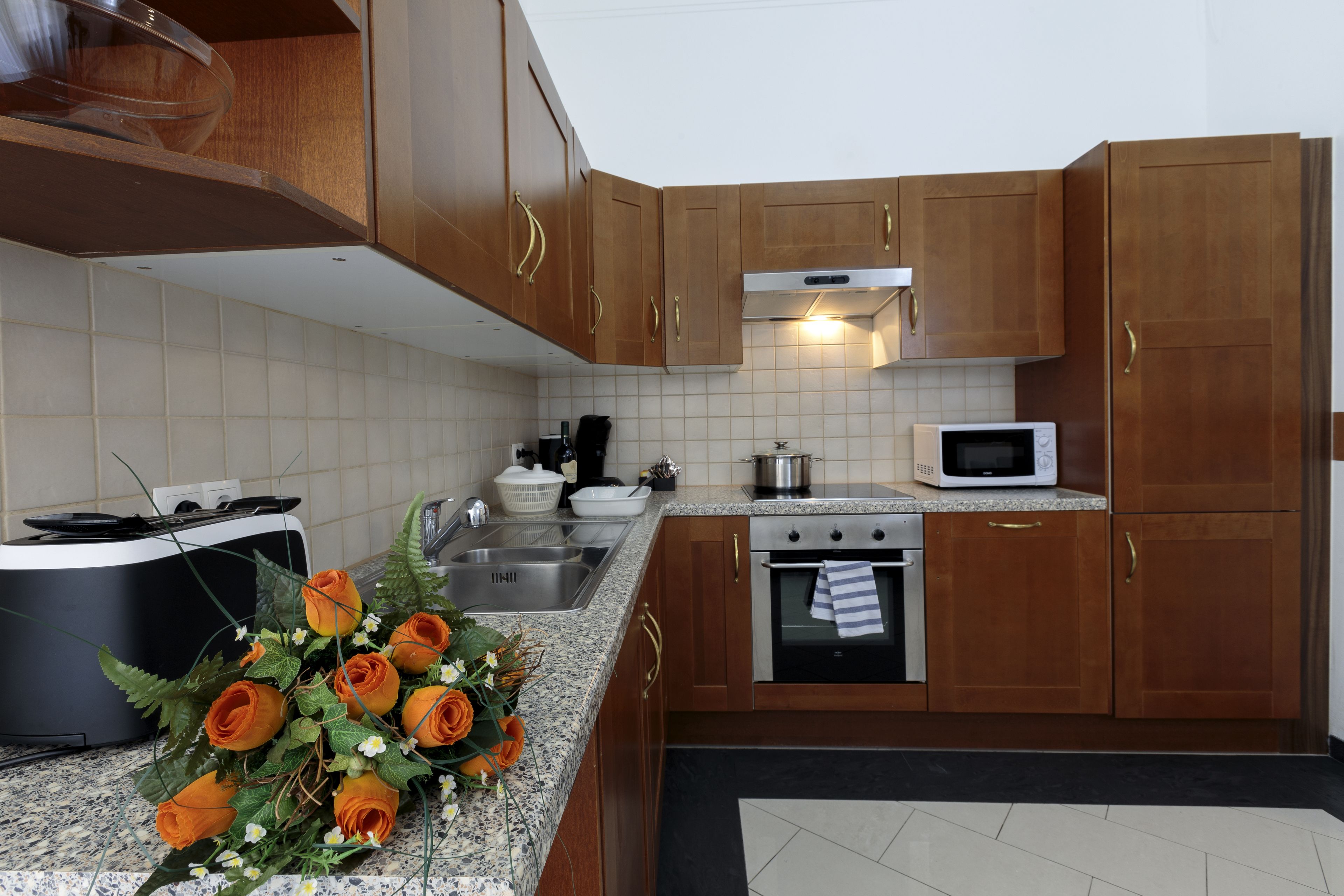 Una cocina con armarios de madera, un microondas, un horno y un lavamanos.