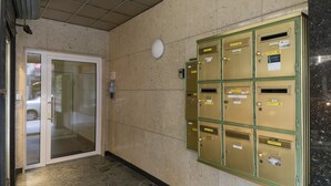 Ein Flur mit Glastür, Brandmelder und einer Reihe goldfarbener Schließfächer.