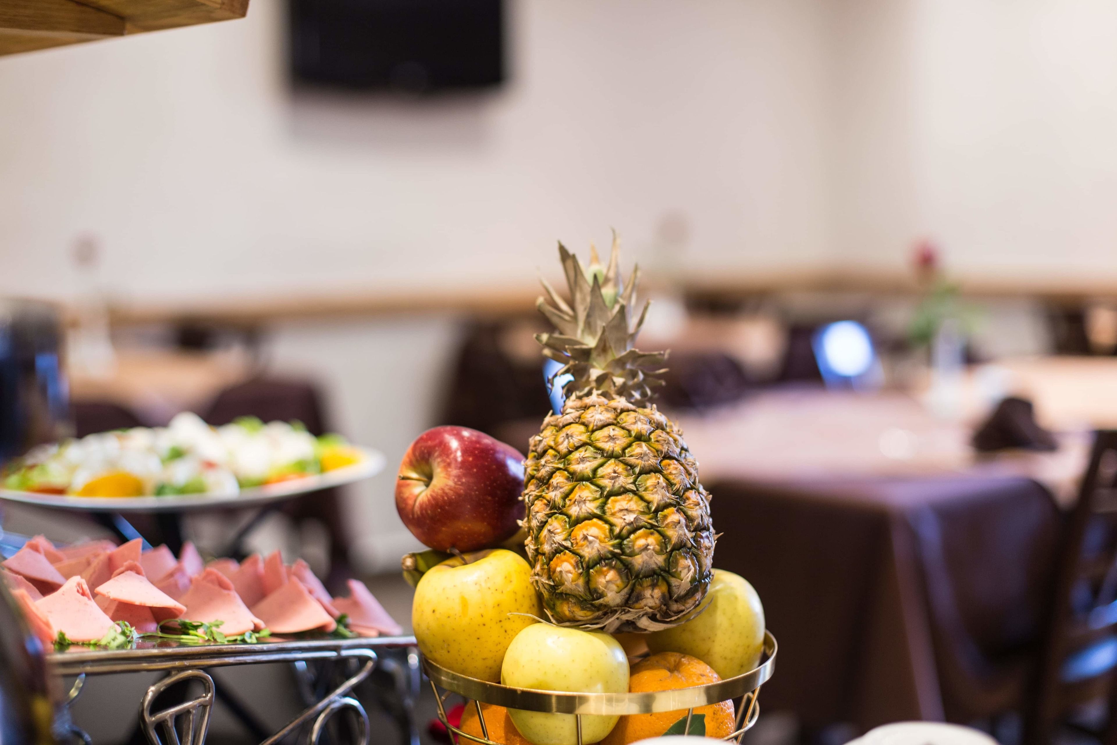 Un buffet proposant une variété de fruits et de viandes, notamment des pommes, des oranges et du jambon.