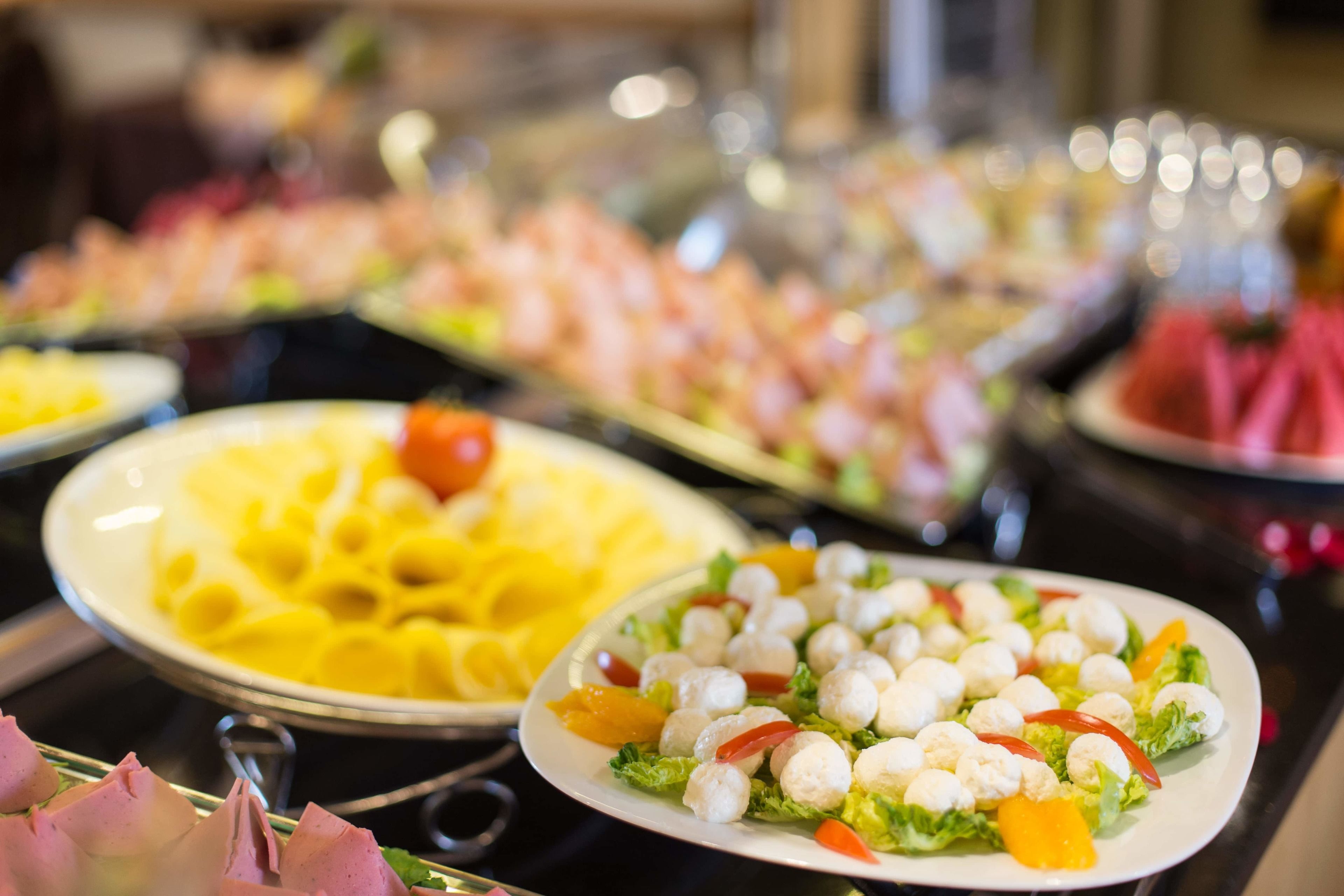 A buffet with various dishes including pasta, salads, and meat.