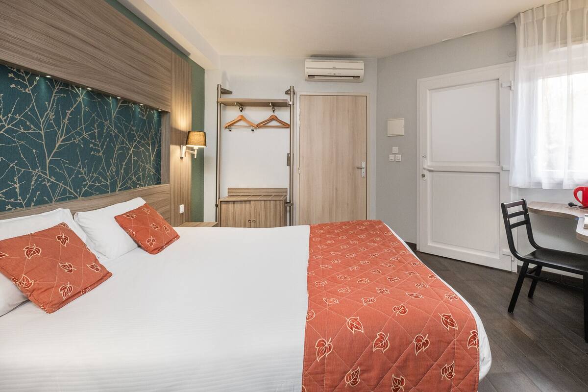 Une chambre d’hôtel équipée d’un lit, d’un bureau, d’une chaise, d’une armoire et d’un porte-vêtements.