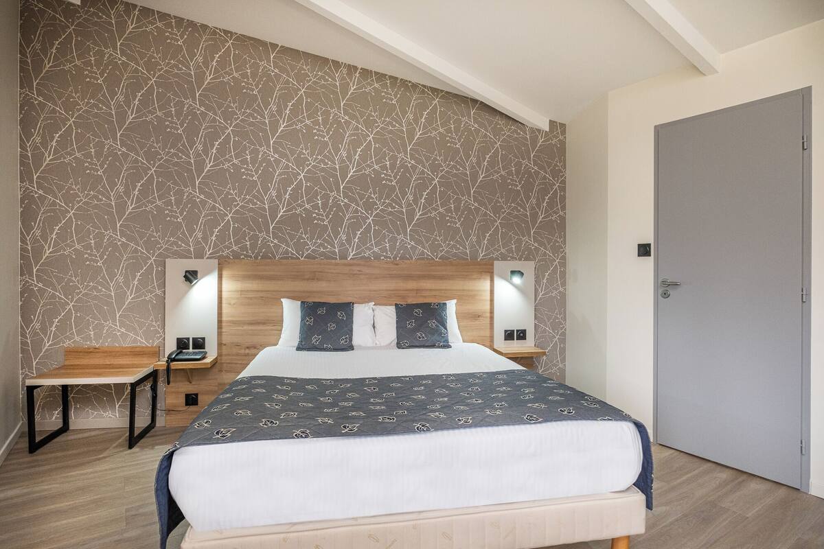 Une chambre à coucher moderne avec un grand lit, deux tables de chevet et une petite table d’appoint.