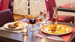 A dining table with plates of food, wine glasses, and a candle. - Charme Hôtel Montbéliard (Arbouans)