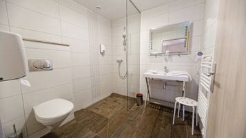 Une salle de bain comprenant des toilettes, une douche, un lavabo et un miroir.