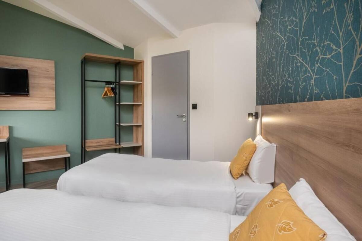 Une chambre d’hôtel avec deux lits, un téléviseur fixé au mur, une armoire et une porte.