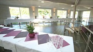 A spacious indoor area with a long table set for a meeting or event, large windows allowing natural light, and a balcony with railings. - Charme Hôtel Montbéliard (Arbouans)