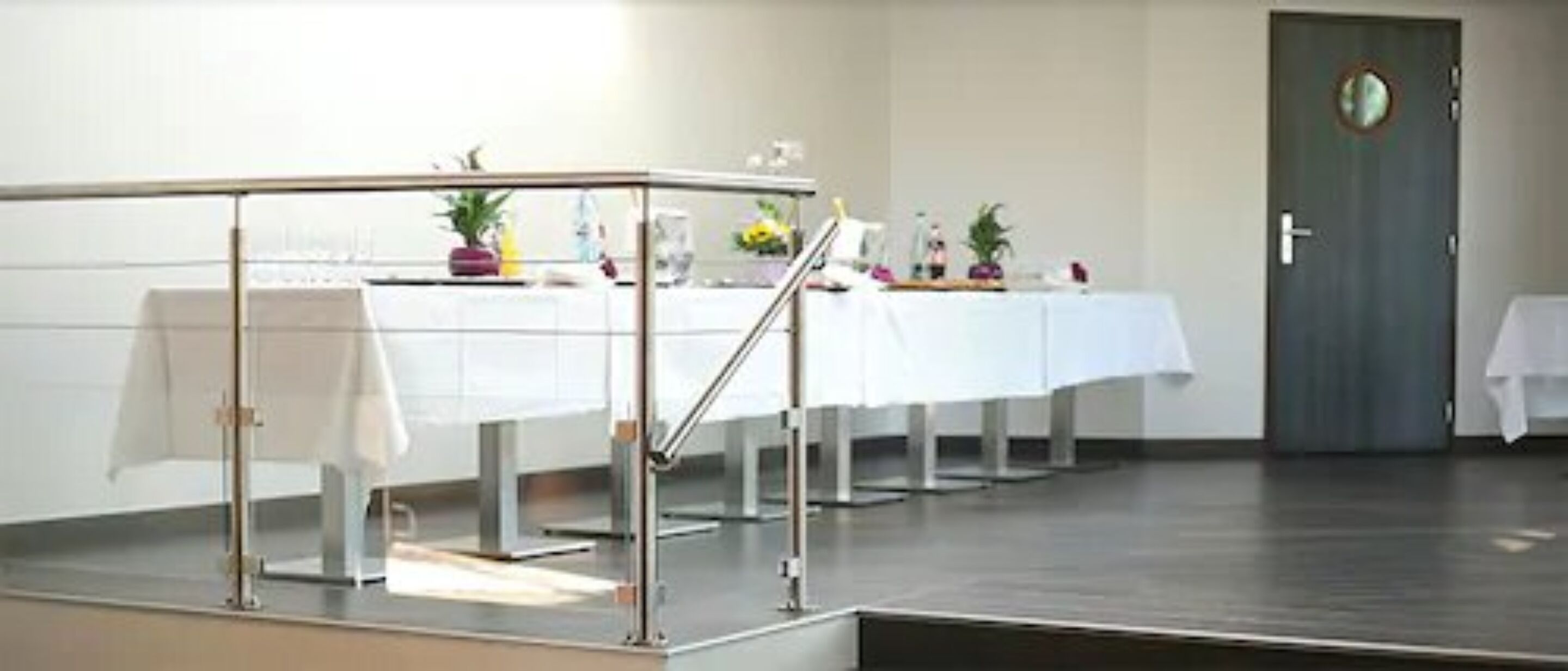 A conference room with a long table, chairs, and a railing.