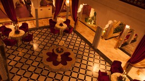 A luxurious interior with a checkered floor, round tables with candles, and red velvet chairs. - Villa Des Ambassadors (Rabat)