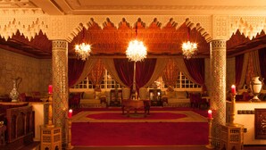 A richly decorated room with ornate columns, a red carpet, and a chandelier. - Villa Des Ambassadors (Rabat)