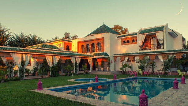 A large, luxurious villa with a swimming pool, multiple outdoor seating areas, and a well-maintained garden. - Villa Des Ambassadors (Rabat)
