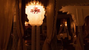 An ornate interior with a chandelier, patterned columns, and draped curtains. - Villa Des Ambassadors (Rabat)