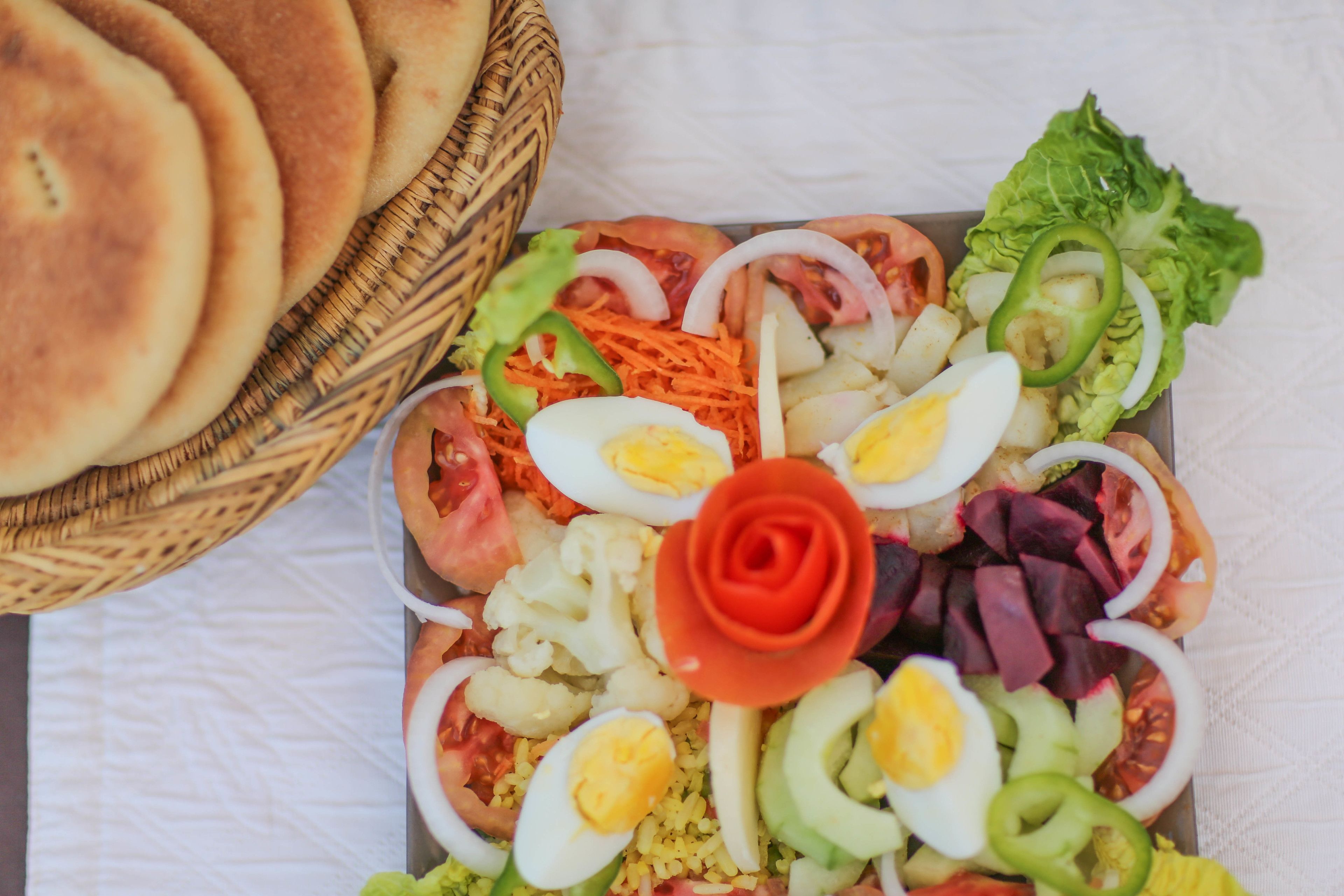 A tray of food with various items including eggs, vegetables, and a rose-shaped decoration.