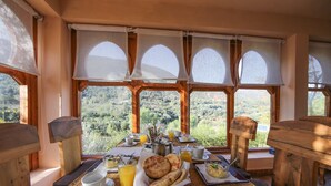 A breakfast table with a view of the mountains, wooden furniture, and a basket of bread. - Kasbah Africa (Ouirgane)