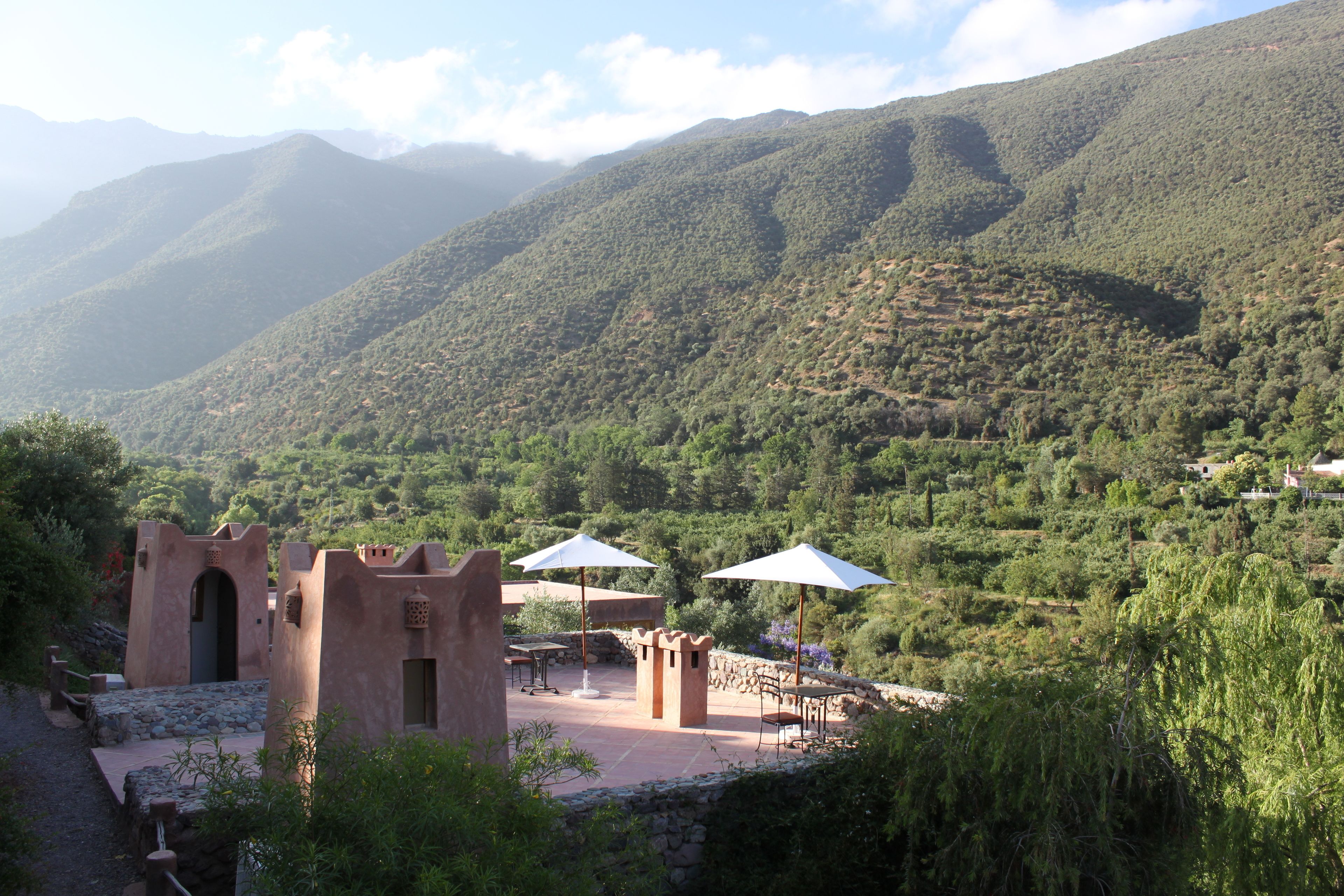 A rustic outdoor seating area with stone walls and a view of a mountainous landscape.