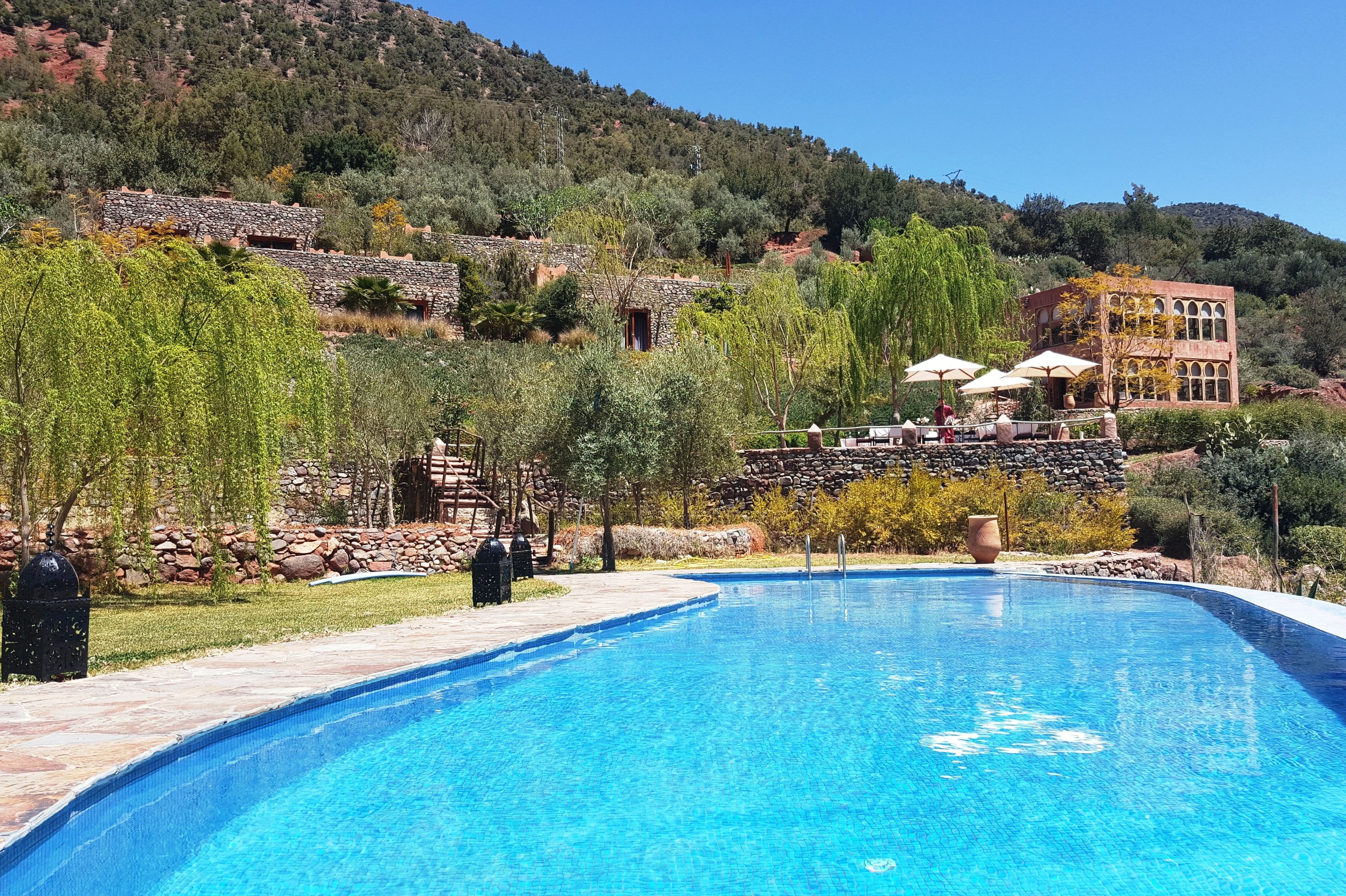A swimming pool with stone architecture and a view of a hillside.