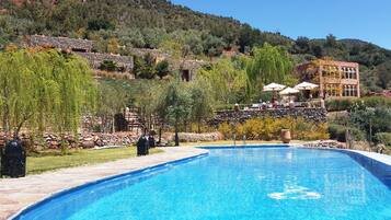 A swimming pool with stone architecture and a view of a hillside.