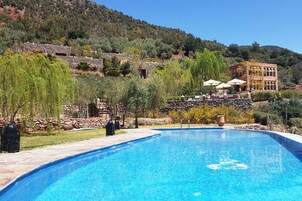 Una piscina con arquitectura de piedra y vistas a una colina.