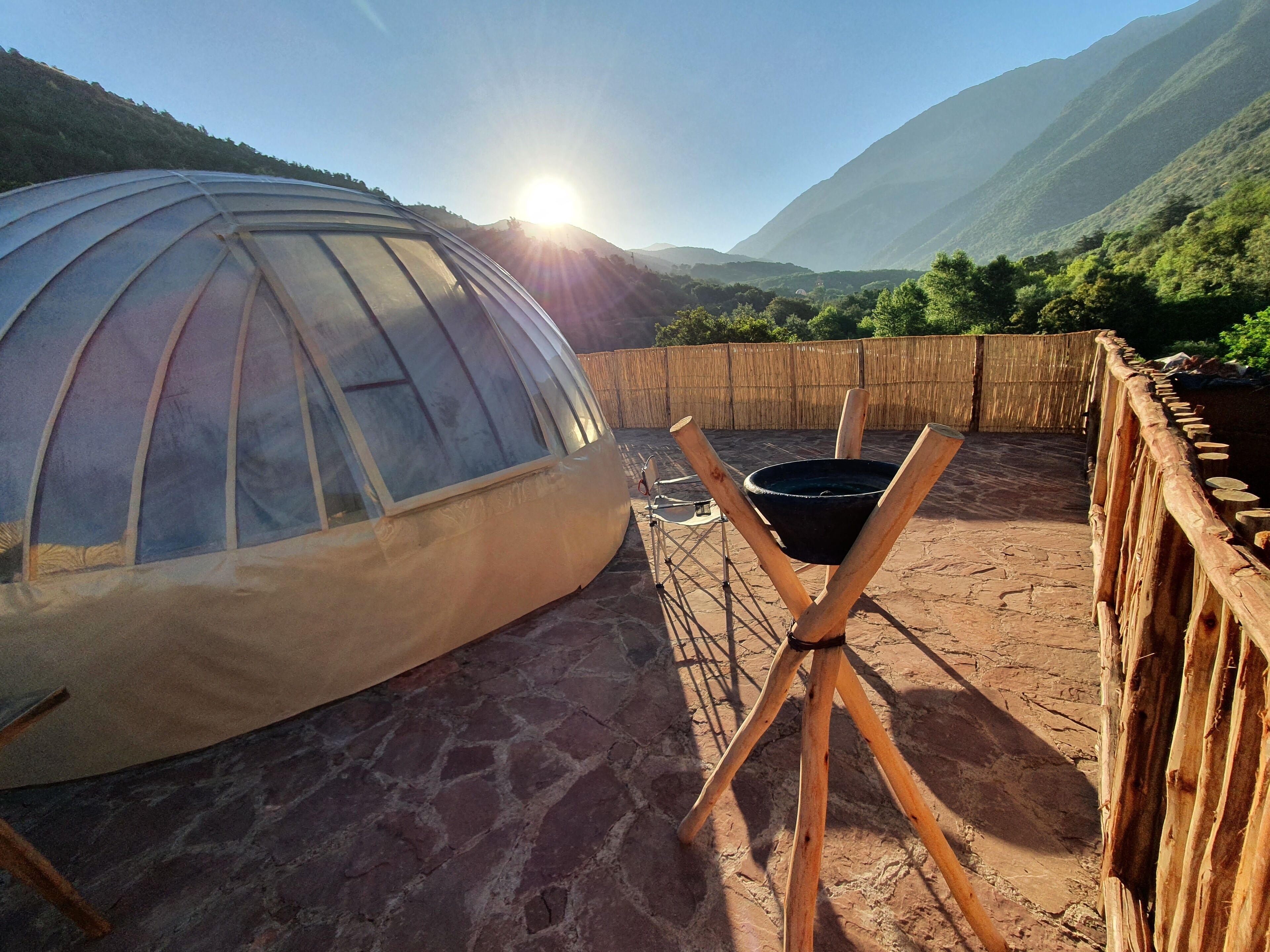 A dome-shaped structure with a wooden fence and a tripod stand in the foreground.