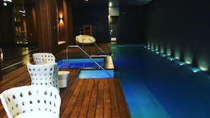 A pool area with wooden flooring, white chairs, and a small pool. - Apartments Melbourne Domain - New Quay Docklands (Docklands)