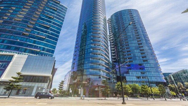 A modern high-rise building with a curved facade and reflective glass windows. - Apartments Melbourne Domain - New Quay Docklands (Docklands)