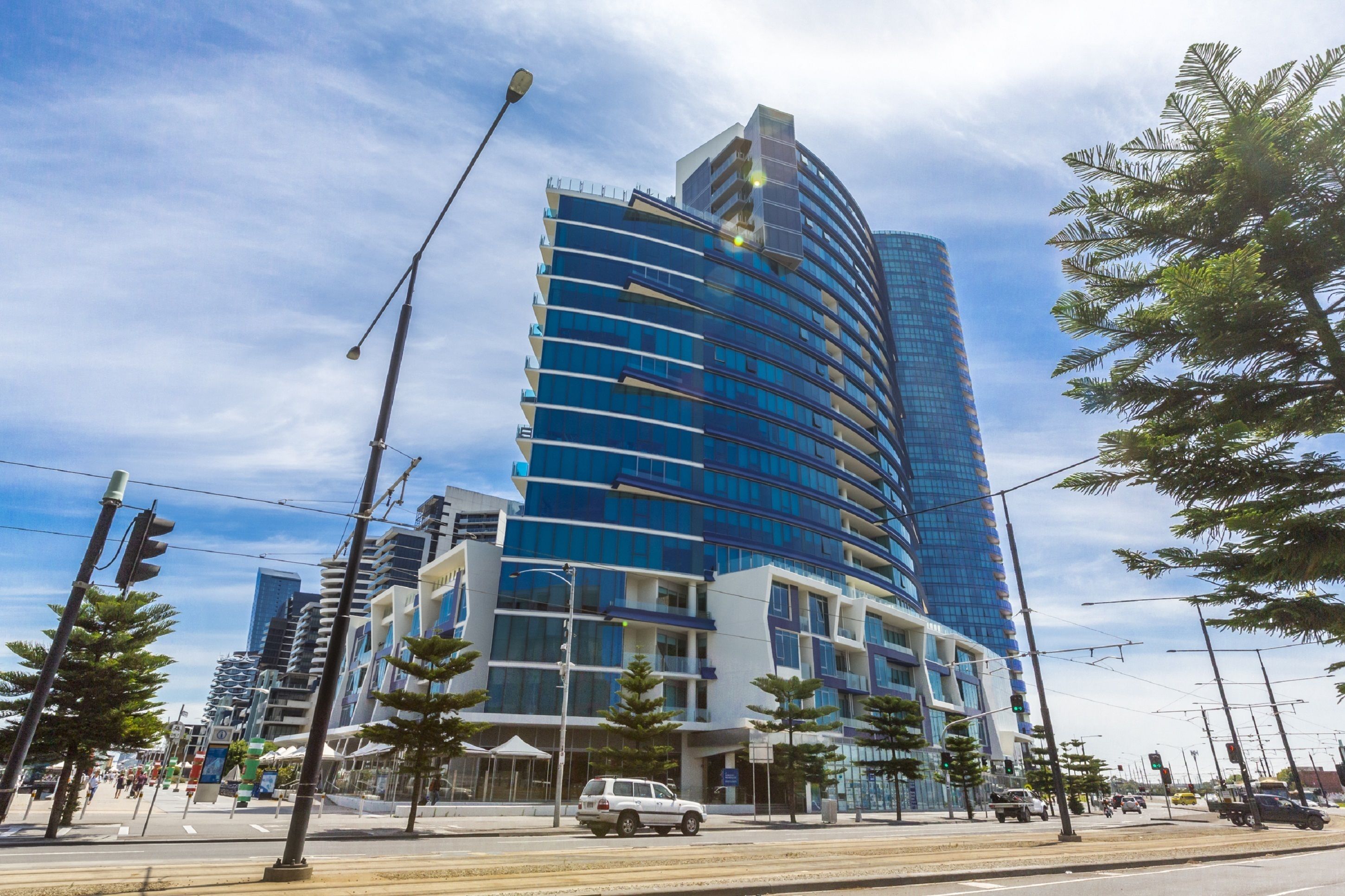 A modern multi-story hotel with a curved facade, large windows, and a prominent entrance.