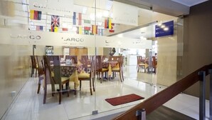 A hotel lobby with a glass partition, multiple dining tables, and chairs. - Suites Larco 656 (Lima)