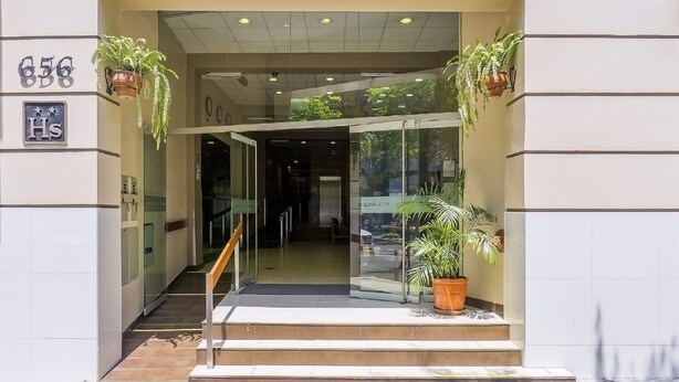 A hotel entrance with a glass door, a staircase leading up, and potted plants on either side. - Suites Larco 656 (Lima)