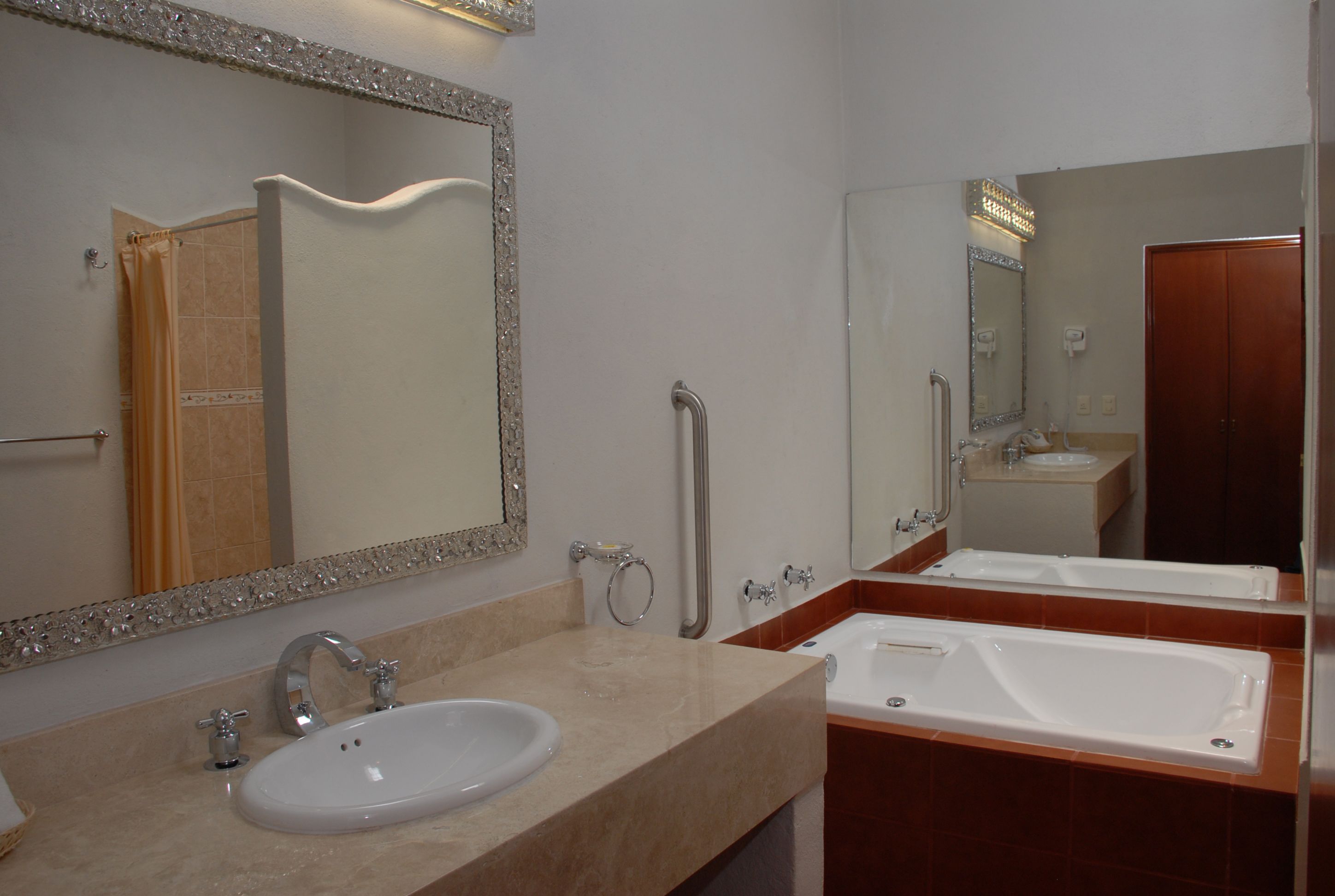 Une salle de bain équipée d’un lavabo, de deux miroirs, d’une douche et de toilettes.