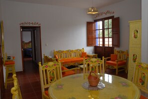 A dining area with a round table, chairs, and a window with wooden shutters. - Hotel Hacienda Don Cenobio (San Pablo Villa de Mitla)