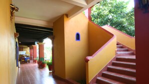 A corridor with tiled flooring, a staircase with red steps, and a small window. - Hotel Hacienda Don Cenobio (San Pablo Villa de Mitla)