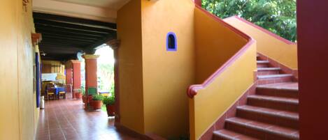 A corridor with tiled flooring, a staircase with red steps, and a small window.