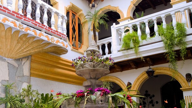 A courtyard with a central fountain surrounded by potted plants and a tiled floor. - Hotel Ciudad Condal (Antigua Guatemala)