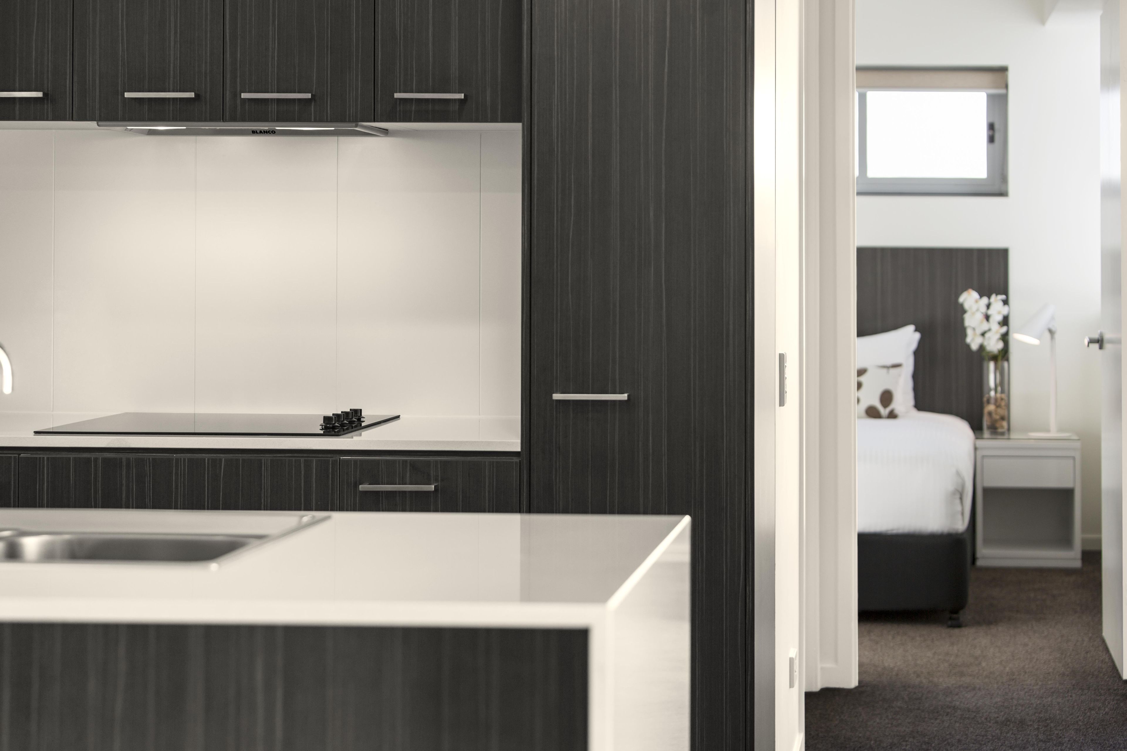 A modern kitchen with dark cabinetry and a white countertop.