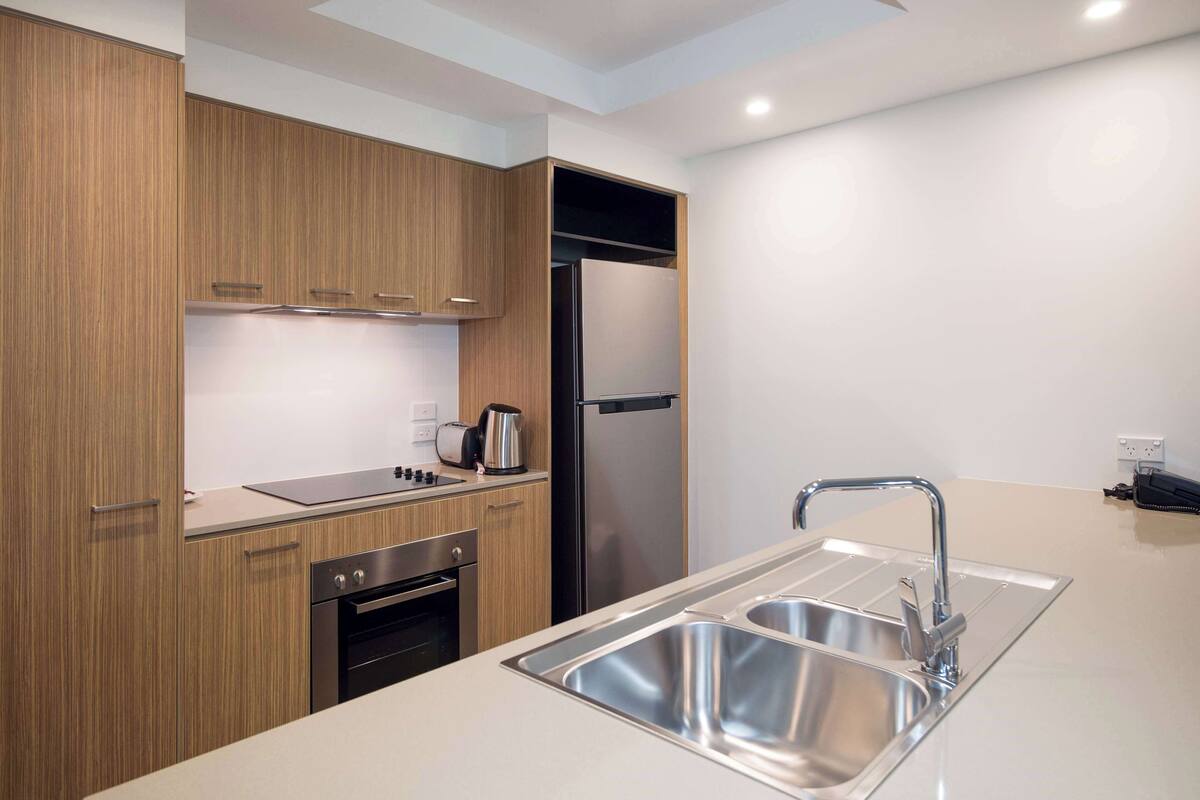 A modern kitchen with wooden cabinets, stainless steel appliances, and a double sink.
