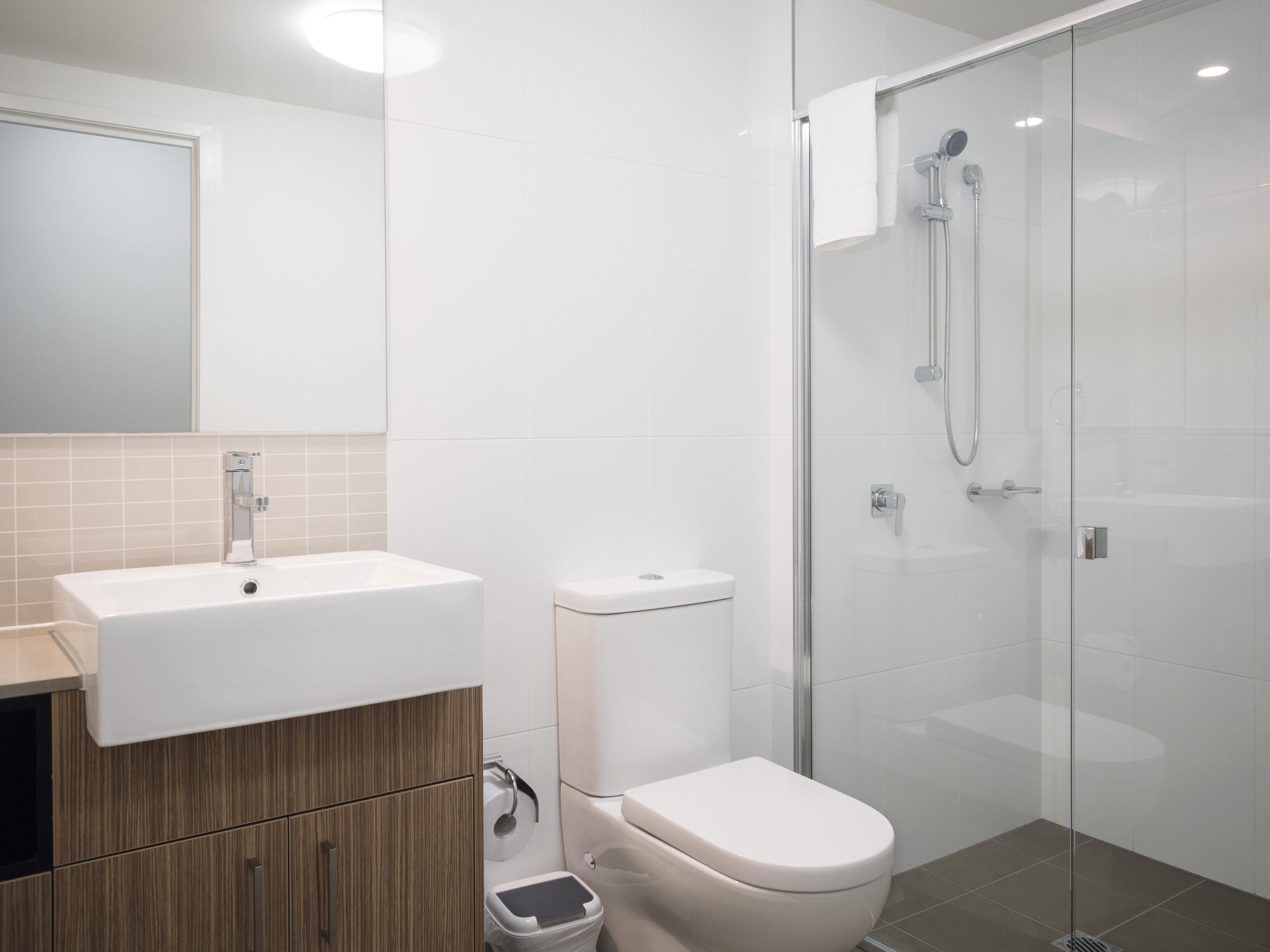 A modern bathroom with a glass-enclosed shower, a white sink, and a toilet.