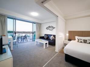 A hotel room with a balcony, a bed, a desk, and a chair. - Oaks Mackay Rivermarque Hotel (Mackay)