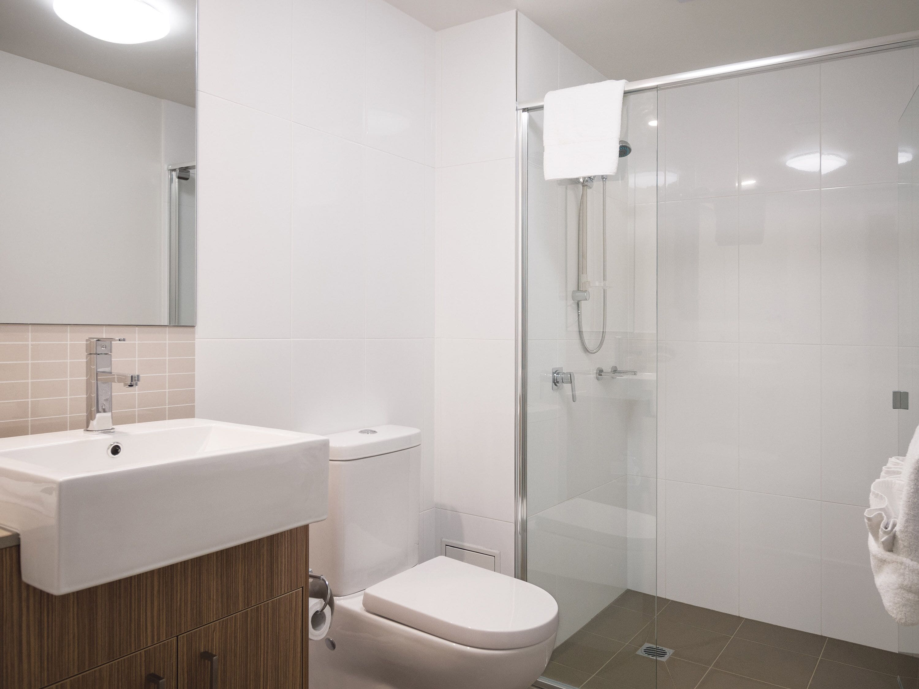 Ein modernes Badezimmer mit Waschbecken, Toilette und einer Duschkabine aus Glas.